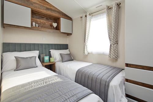 Un dormitorio con dos camas y una ventana. en FRESHWATER BEACH HOLIDAY HOME, en Burton Bradstock