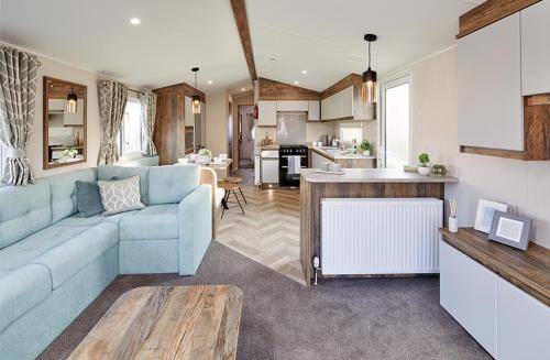 a living room with a blue couch and a kitchen at FRESHWATER BEACH HOLIDAY HOME in Burton Bradstock