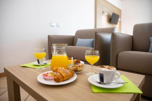 a table with breakfast foods and glasses of orange juice at Pegasus Hotel in Sassari