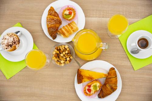 a table with plates of breakfast foods and cups of orange juice at Pegasus Hotel in Sassari
