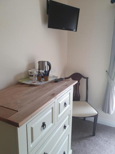 a white cabinet with a wooden counter top and a chair at Willards B&B in Bundoran
