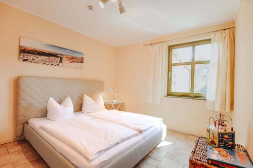 una camera da letto con un letto bianco e una finestra di Ferienwohnung Am Leuchtfeuer EG a Wustrow