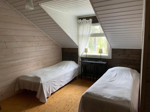 a attic bedroom with two beds and a window at Purola Farm Guesthouse in Saarijärvi