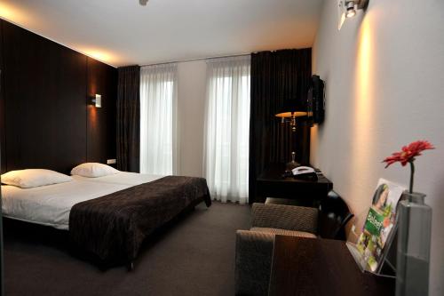 a hotel room with a bed and a chair at Golden Tulip West Ende in Helmond