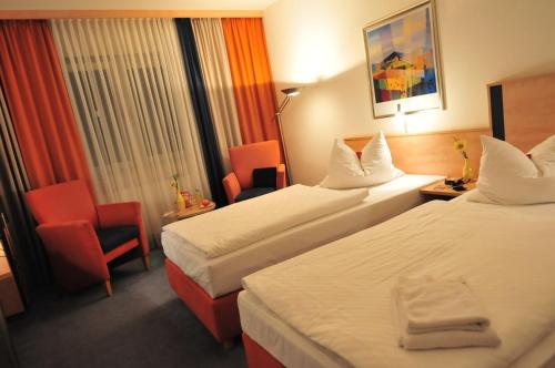 una habitación de hotel con 2 camas y una silla en AKZENT Hotel Stadt Schlüchtern ***S, en Schlüchtern