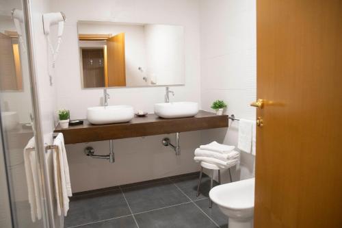 a bathroom with two sinks and a toilet at Pegasus Hotel in Sassari