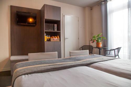 a bedroom with a bed with two chairs and a television at Hotel Pannenkoekhuis Vierwegen in Domburg