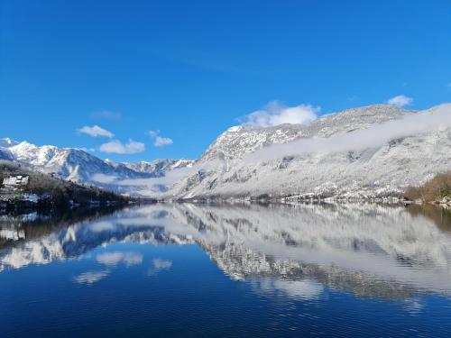 a reflection of snow covered mountains in a lake at Apartments Irena in Bohinj