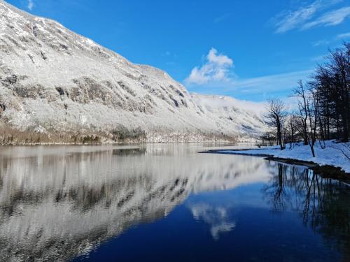 a snow covered mountain reflecting in a lake at Apartments Irena in Bohinj