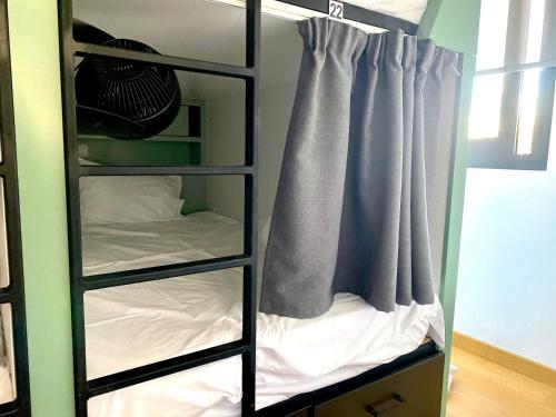 Cette chambre dispose de lits superposés noirs avec un lit et un rideau. dans l'établissement Urban Habitat Capsule Beds, à Nicosie
