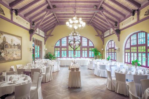 un salón de banquetes con mesas y sillas blancas y una lámpara de araña en Berggasthof Butterberg, en Bischofswerda