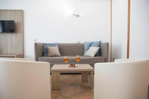 a living room with a couch and two glasses of wine at Pegasus Hotel in Sassari