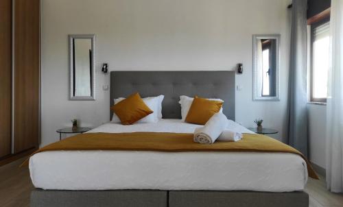1 dormitorio con 1 cama grande con almohadas de color naranja y blanco en Apartamentos na Quinta Altavista do Carvalhal, en Zambujeira do Mar