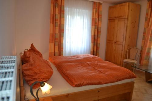 a bedroom with a bed with an orange comforter and a window at Haus Rohskopf in Mallnitz