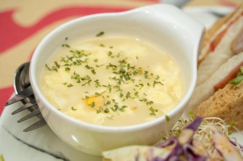 a bowl of soup with chives on a plate with a sandwich at Lusihan B&B in Yuchi