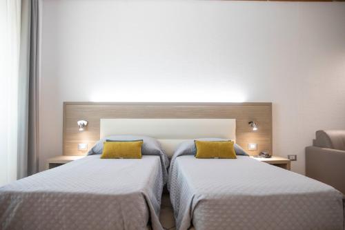 two beds with yellow pillows in a hotel room at Pegasus Hotel in Sassari
