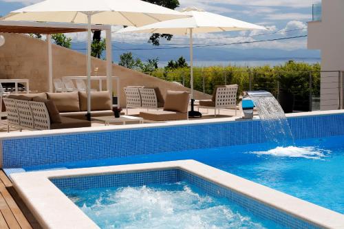 a swimming pool with chairs and an umbrella at MODENA MARIS-heated pool-grill-relax-jacuzzi apartments in Ičići