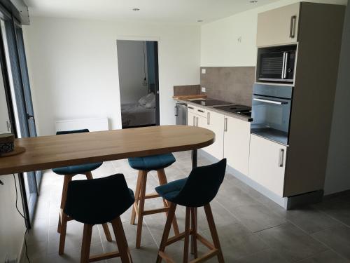 une cuisine avec une table en bois et des chaises bleues dans l'établissement MAISON DU GABAS D'ANNA & ROSE, à Limendous