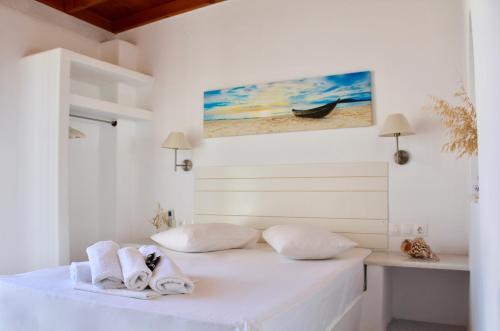 a white bedroom with a bed with towels on it at Aegeo Inn in Antiparos