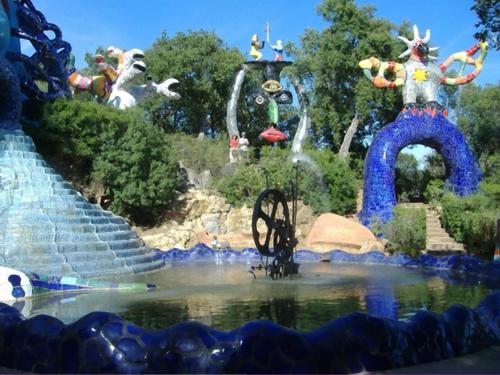 a fountain in the middle of a pond in a park at Hotel La Torricella in Capalbio