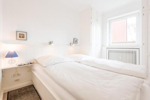 ein weißes Schlafzimmer mit 2 Betten und einem Fenster in der Unterkunft Haus Atrium Wohnung 19 in Westerland