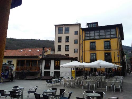 an outdoor patio with tables and chairs and buildings at La Refierta in Cangas del Narcea