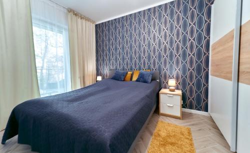Un dormitorio con una cama azul y una ventana en LAGUNA Apartament Polanica Residence 10, en Polanica-Zdrój