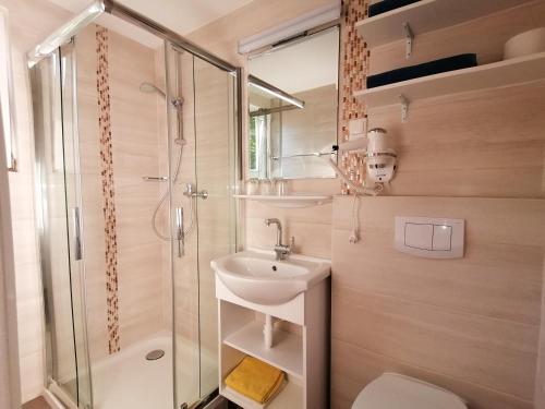 ein Bad mit einem Waschbecken, einer Dusche und einem WC in der Unterkunft Strandpension Liane in Sankt Kanzian am Klopeiner See