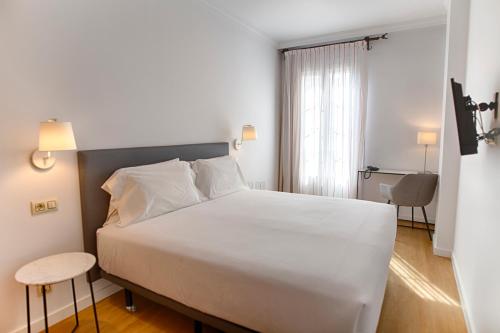 Un dormitorio con una gran cama blanca y una ventana en Sercotel Tribuna Málaga, en Málaga