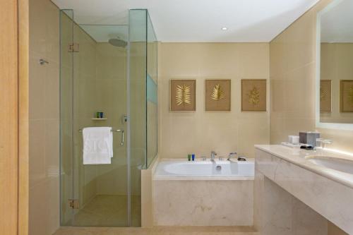 a bathroom with a shower and a sink and a tub at ASTON Gresik Hotel & Conference Center in Gresik