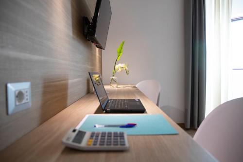 a laptop computer sitting on a wooden table with a pen at Pegasus Hotel in Sassari