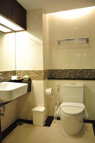 ein Badezimmer mit weißer Toilette und Waschbecken in der Unterkunft August Suites in Pattaya