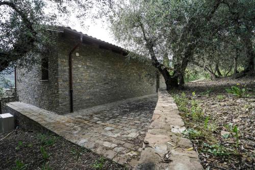a brick building with a tree next to a sidewalk at B&B il Pianolo in Perinaldo