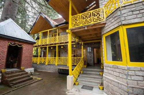 a building with a yellow deck and stairs on it at The Hosteller Manali in Manāli