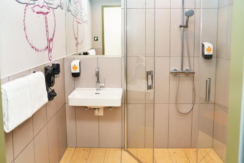 W łazience znajduje się prysznic i umywalka. w obiekcie McDreams Hotel München-Airport w mieście Eching