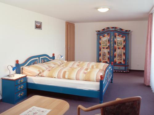 a bedroom with a blue bed and a table at Panorama Hotel Freudenberg in Appenzell