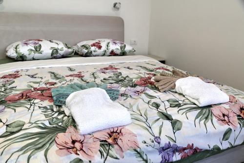 un lit avec une couette à fleurs et deux serviettes dans l'établissement Apartmani Ateljević, à Trebinje