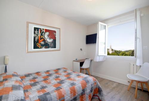 1 dormitorio con cama, ventana y escritorio en Hôtel Montfort, en Lourdes