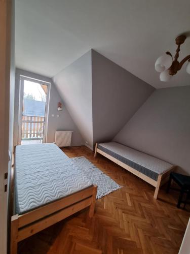 Cette chambre mansardée comprend un lit et une fenêtre. dans l'établissement Apartament Droga na Bystre 9a, à Zakopane