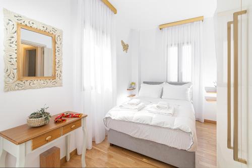 Habitación blanca con cama y espejo en Villa Dafni - Lindos en Líndos