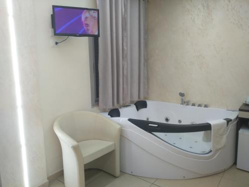 uma banheira branca na casa de banho com uma televisão na parede em B&B Vistamareblu em San Foca