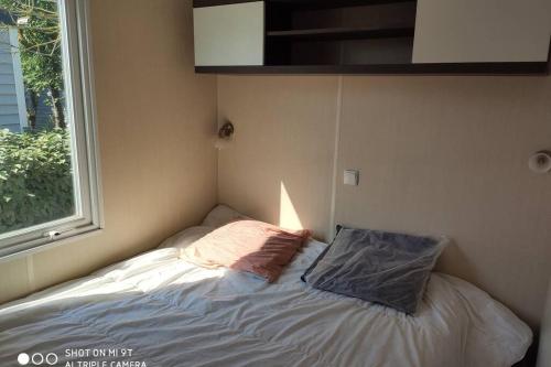 un petit lit dans une chambre avec une fenêtre dans l'établissement Mobilhome climatisé et ombragé, à Port-la-Nouvelle