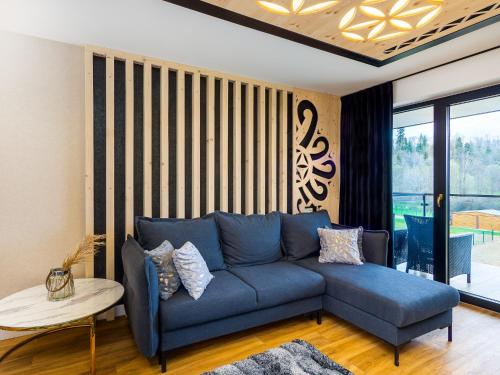 a blue couch in a living room with a window at Aparthotel Góralski Spa 2 in Białka Tatrzanska