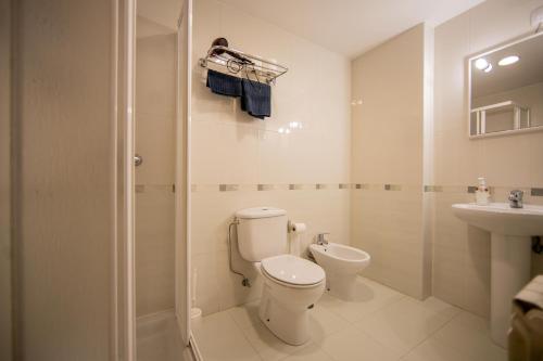 Baño blanco con aseo y lavamanos en Cantares-NOJA ROOMS, en O Pedrouzo