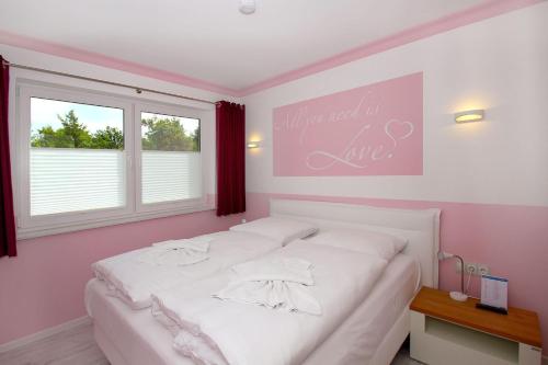 a bedroom with a white bed and a pink wall at Ruegen-Beach-House-Haus-Palstek in Göhren