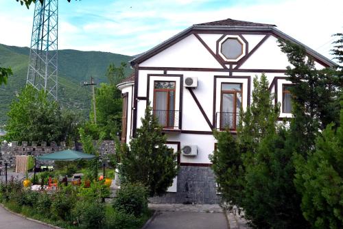 a white house with a garden in front of it at Ansera 55 Hotel Sheki in Sheki