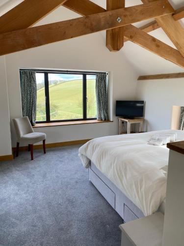 a bedroom with a bed and a chair and a window at Creber Cottage in Totnes