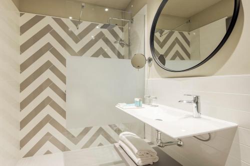 a bathroom with a sink and a mirror at Ilunion Alcora Sevilla in San Juan de Aznalfarache