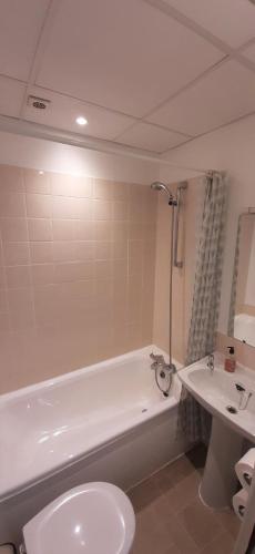 a bathroom with a tub and a toilet and a sink at Shipping Lanes Hotel in Morecambe