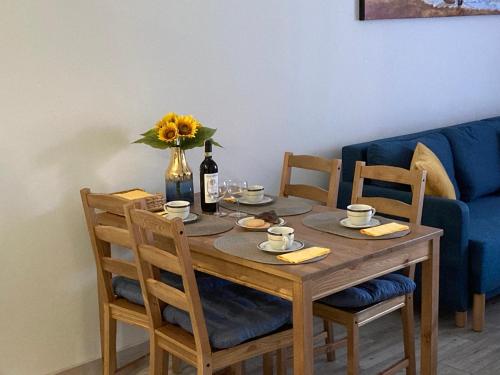a wooden table with a vase of flowers and a bottle of wine at Apartament Łebska Ostoja in Żarnowska